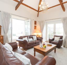 A living room with brown leather sofas a wooden coffee table and a wooden cabinet at Farnelea in West Fleetham near Seahouses