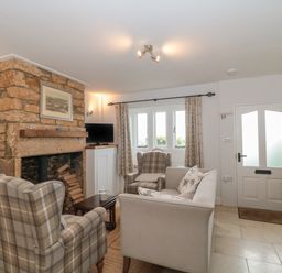 A living room with stone fireplace plaid armchairs sofa and a television at Scrambles Cottage in Stoke-Sub-Hamdon Somerset
