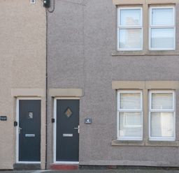 Two adjacent houses with dark doors and four white framed windows at 4 Percy Street in Amble