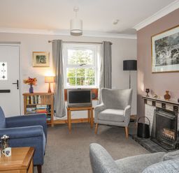 A living room with armchairs a fireplace a small television window and a bookcase at Ty Eiddew Ivy House Llanystumdwy near Criccieth