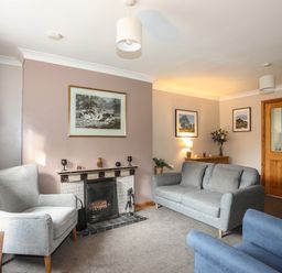 A living room with a fireplace two sofas armchair and framed pictures at Ty Eiddew Ivy House Llanystumdwy near Criccieth