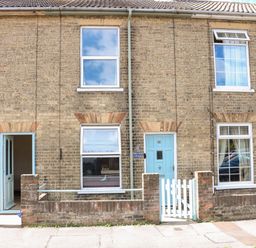 The front exterior of a brick terraced house with light blue doors and windows at Sole Bay Cottage in Lowestoft