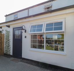 Outside view of a white building with a black door and two windows at 9 Station Cottages in Belford