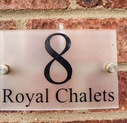 A house number sign with the number 8 and the text Royal Chalets on a brick wall at 8 Royal Chalet Park in Mundesley