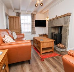 A living room with orange leather sofas a wooden coffee table and a stone fireplace at Braeside in Fylingthorpe