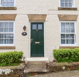 A green front door with two windows on either side and shrubs in front at Braeside in Fylingthorpe
