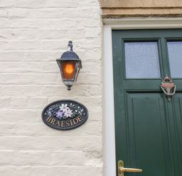 A house exterior with a green door a wall light and a plaque that says Braeside in Fylingthorpe