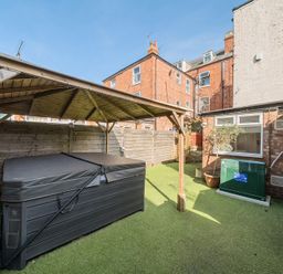 A backyard with a covered hot tub artificial grass and brick buildings at Bridlington Bay House in Bridlington