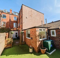 An outdoor area with brick buildings wooden fences greenery and potted plants at Bridlington Bay House in Bridlington