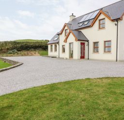 A house with a gravel driveway and grass lawn at Ballycahane in Castletownshend County Cork
