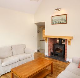 A living room with two beige couches a wooden coffee table and a fireplace with a wood-burning stove at Ballycahane in Castletownshend County Cork