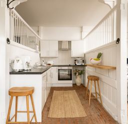 A kitchen with stools and an oven at Stable in Blandford Forum