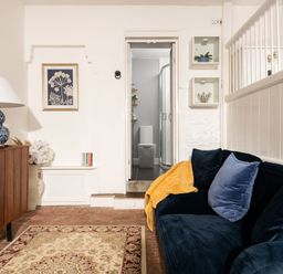A living room with a sofa and a view of a bathroom door at Stable in Blandford Forum