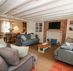 A living room with three sofas a coffee table a wall-mounted television and a dining table with chairs at Dyffryn Cottage in Aberporth