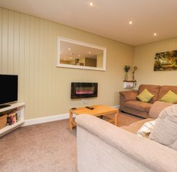 A living room with two sofas a wooden coffee table a wall-mounted electric fireplace and a television at Oak Lodge in Goosnargh
