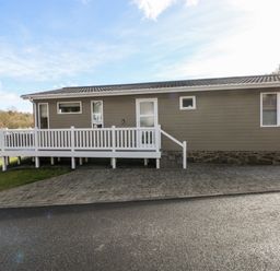 Exterior view of a single story house with a white railing and paved driveway at Lodge 53 in Stepaside near Kilgetty