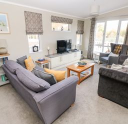 A living room with sofas armchair coffee table and television at Lodge 53 Stepaside near Kilgetty