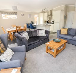 An open plan living room with two sofas an armchair a coffee table and a dining table with chairs at Lodge 53 Stepaside near Kilgetty