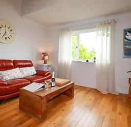 A living room with a sofa, coffee table and window at Sea View in St Austell