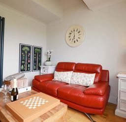 A living room with a red sofa and coffee table at Sea View in St Austell