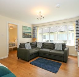 A living room with a dark grey sectional sofa and patterned cushions at 1 The Dell in Mundesley