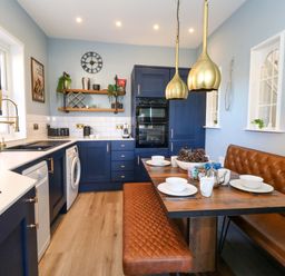 A kitchen with blue cabinets and wooden table at The Old Post Office in Weymouth