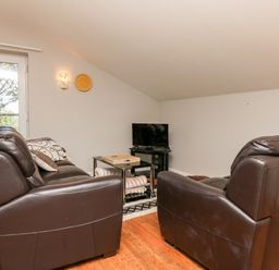 A living room with two brown leather sofas a glass coffee table and a television at Hazelwood Lodge in High Bickington