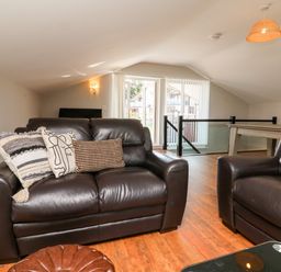 A living room with leather sofas wooden floor and a pool table at Hazelwood Lodge in High Bickington