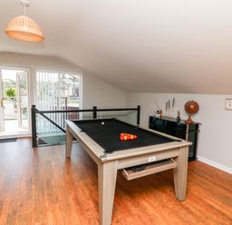 A room with a pool table near glass doors and a black cabinet with decorative items at Hazelwood Lodge in High Bickington