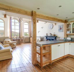 An open-plan kitchen and living area with wooden floors and beams at St Marks School House in Nant-Glas near Rhayader