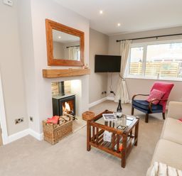 A living room with a fireplace mirror armchair sofa coffee table and window at Willows in Corbridge