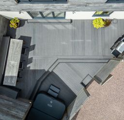 A rooftop patio with a dining table and chairs a barbecue and plants on a deck at The Farmhouse in Llanfechell