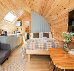 A pod interior with a bed kitchen area sofa dining table and television at Llugwy Pod in Capel Garmon near Betws-Y-Coed