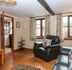A living room with leather armchairs wooden floors curtains with deer patterns and a wooden coffee table at Northwood Barn in Okehampton