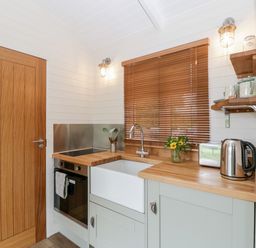 A kitchen with wooden countertops a white sink a kettle toaster and a window with blinds at Willow Kemble