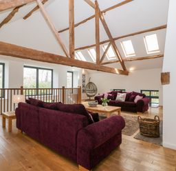 A sitting area with purple sofas a wooden coffee table and exposed wooden beams at Owl Barn Marston Stannett near Leominster