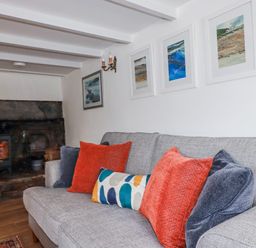 A living room with a sofa and fireplace at Ivy Cottage Trenale near Tintagel