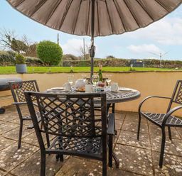 An outdoor dining area with a table and chairs at Ivy Cottage in Trenale near Tintagel