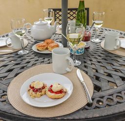 An outdoor dining area with a tea set and plates of scones at Ivy Cottage in Trenale near Tintagel