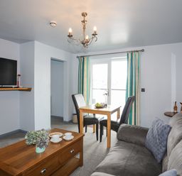 A living room with a grey sofa a wooden coffee table two black chairs and a wooden dining table at Tegid Lakeside - Bala Lake in Bala