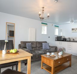 A living room with a sofa a coffee table and a dining table next to a kitchen at Tegid Lakeside - Bala Lake in Bala