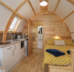 A small wooden cabin interior with a kitchenette on the left and a bed on the right at Mischief in Little Kelk near Bridlington