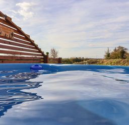 An outdoor hot tub with wooden fencing around and a view of fields and sky at Mischief in Little Kelk near Bridlington
