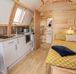 A compact wooden room with a kitchenette and a bed next to a bathroom door at Covey in Little Kelk near Bridlington