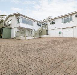 A large white house with multiple windows a balcony and a paved driveway at Willoway in Benllech