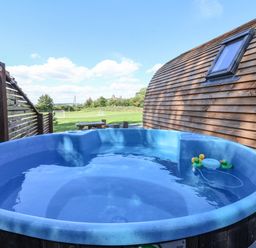An outdoor hot tub with floating rubber ducks next to a wooden building and a picnic table at Bouquet in Little Kelk near Bridlington