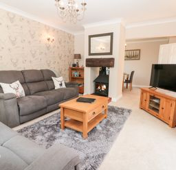 A living room with two grey sofas a wooden coffee table and a fireplace at Church View in Withernwick near Aldbrough