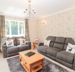 A living room with two gray sofas a wooden coffee table and a window with curtains at Church View in Withernwick near Aldbrough