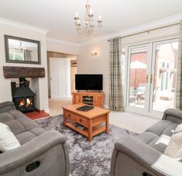 A living room with two sofas a coffee table a fireplace and a television at Church View in Withernwick near Aldbrough