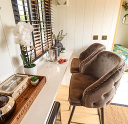 A kitchen counter with two brown bar stools and a tray with teapot and tea boxes at Portland Luxury Glamping in Nottingham